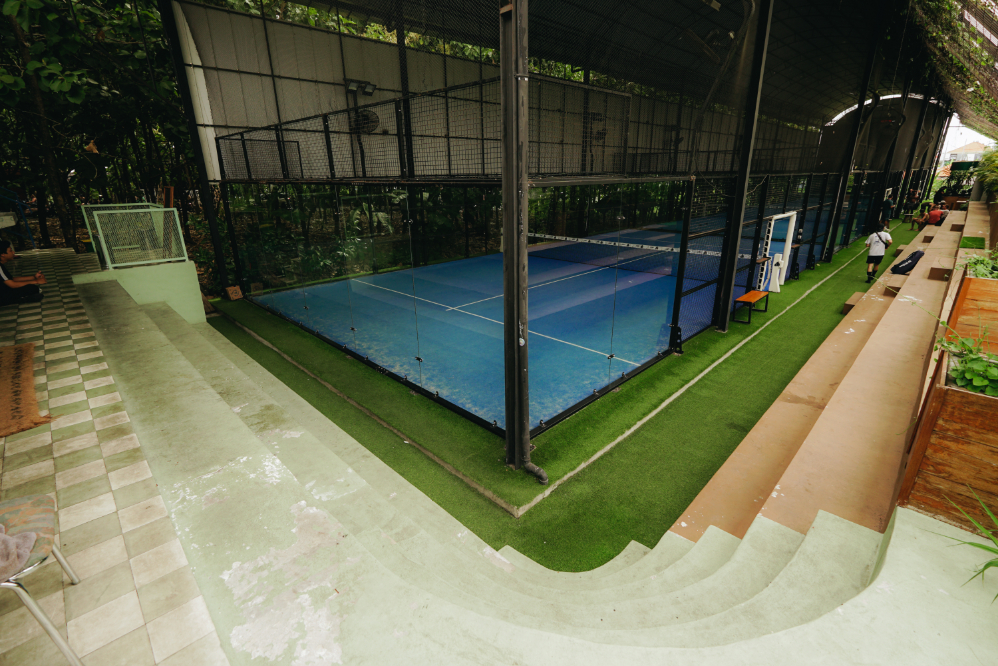 Padel player performing an underarm serve at the baseline