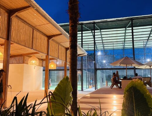 Island Padel Uluwatu illuminated at blue hour - bamboo design with players visible inside the panoramic courts