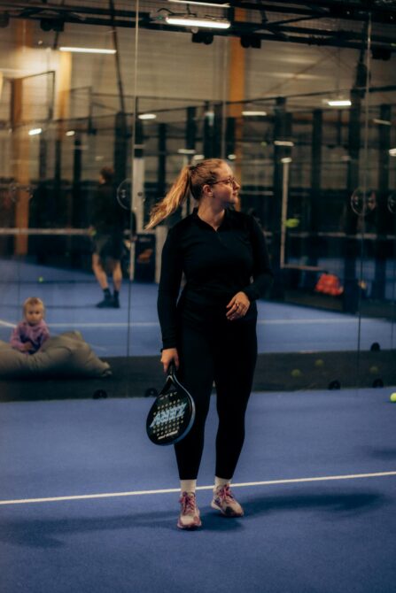 Woman holding a padel racket on an indoor court focused on the game