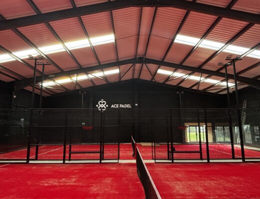 Indoor red padel courts with branded sign at Ace Padel Stoke