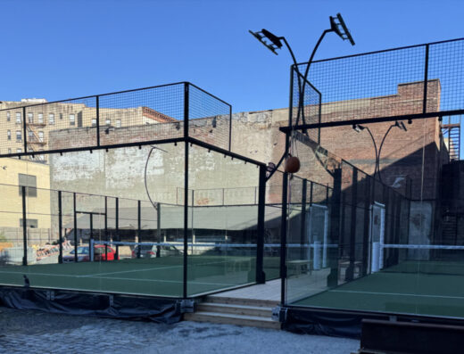 Outdoor glass-walled padel courts among city buildings at Mink Padel, Manhattan