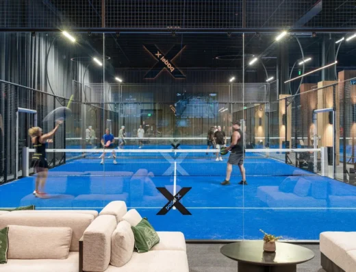 Four players mid rally on a blue indoor padel court at Padel X Boca Raton