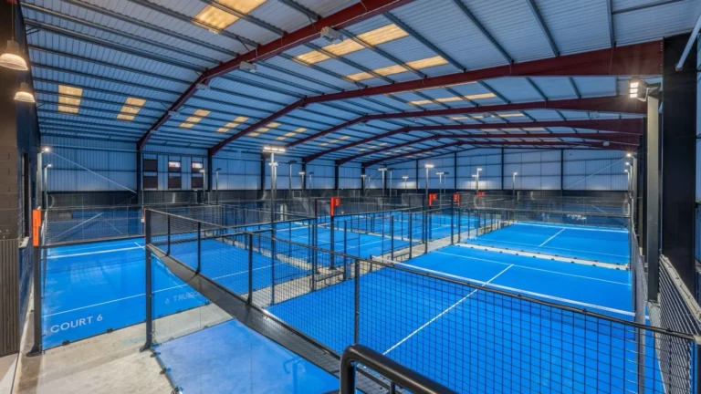 Elevated walkway view over six blue indoor padel courts at Pure Padel Manchester