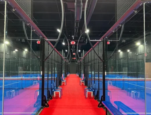 Red carpet walkway between rows of glass padel courts at i95 Padel Club in Miami